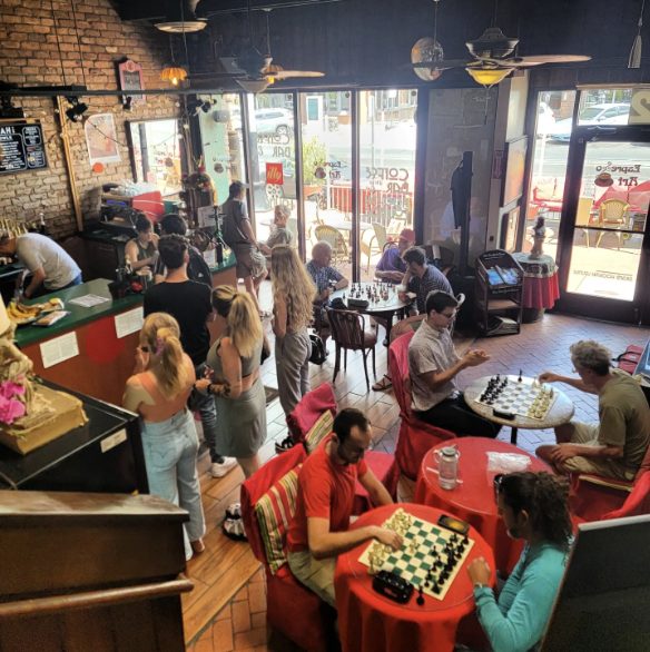Inside Espresso Art Cafe in Tucson, with diverse patrons playing chess, enjoying coffee, and socializing in a vibrant, LGBTQ-friendly setting.