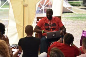 African American man speaks to a group of attendees