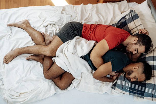 2 men spooning in a bed