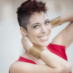 Image of Jenn Hopkins-Reilly with short cropped hair and gold wrist cuffs.