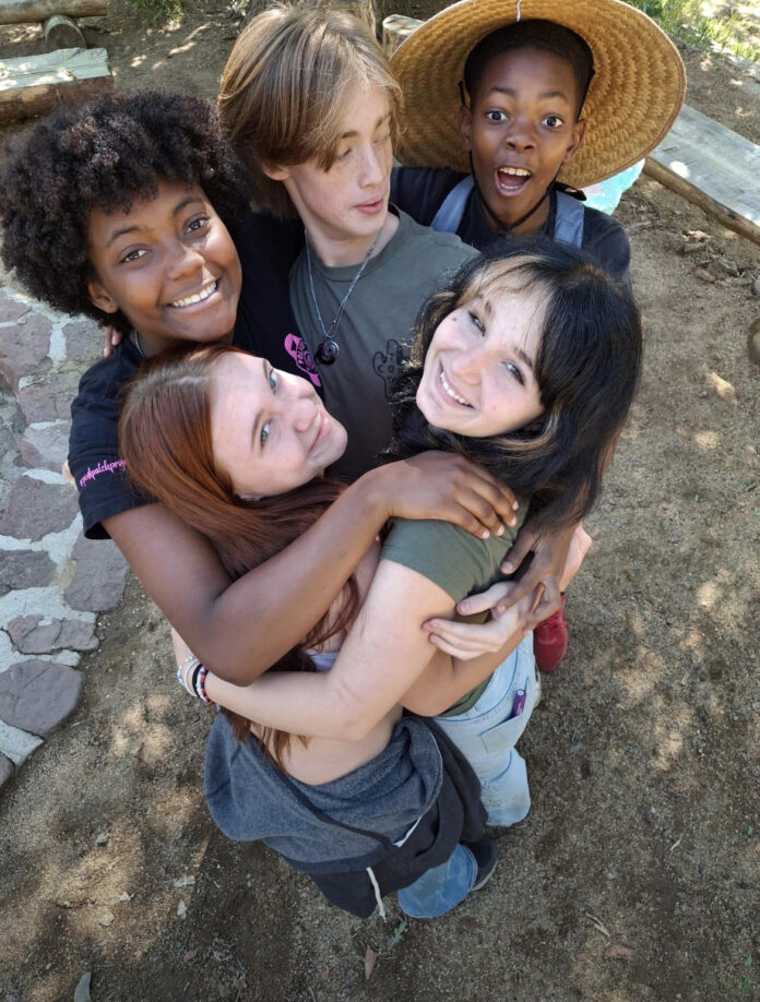 Camp Quest Arizona Friendship and Belonging Camp Quest Arizona campers smiling together in a group hug outdoors