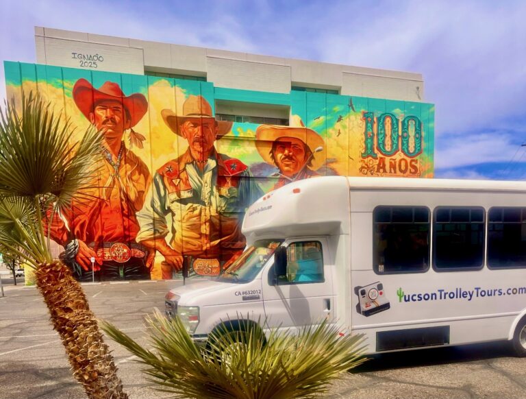 Tucson Trolley Tours bus parked beside a large downtown mural, highlighting Tucson’s public art and mural tour experience.