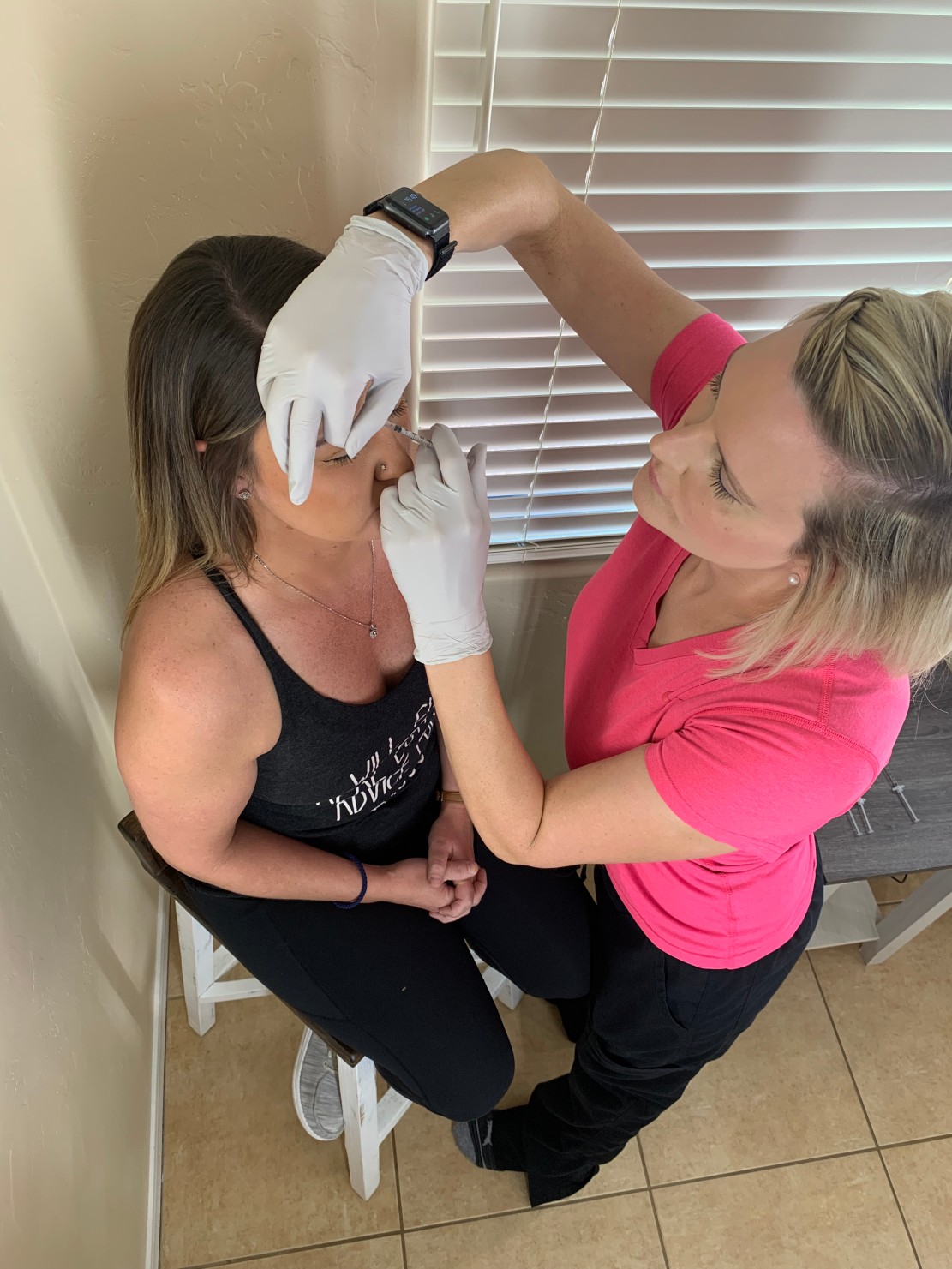 Kelley Beck providing an injectable aesthetic treatment to a seated client.